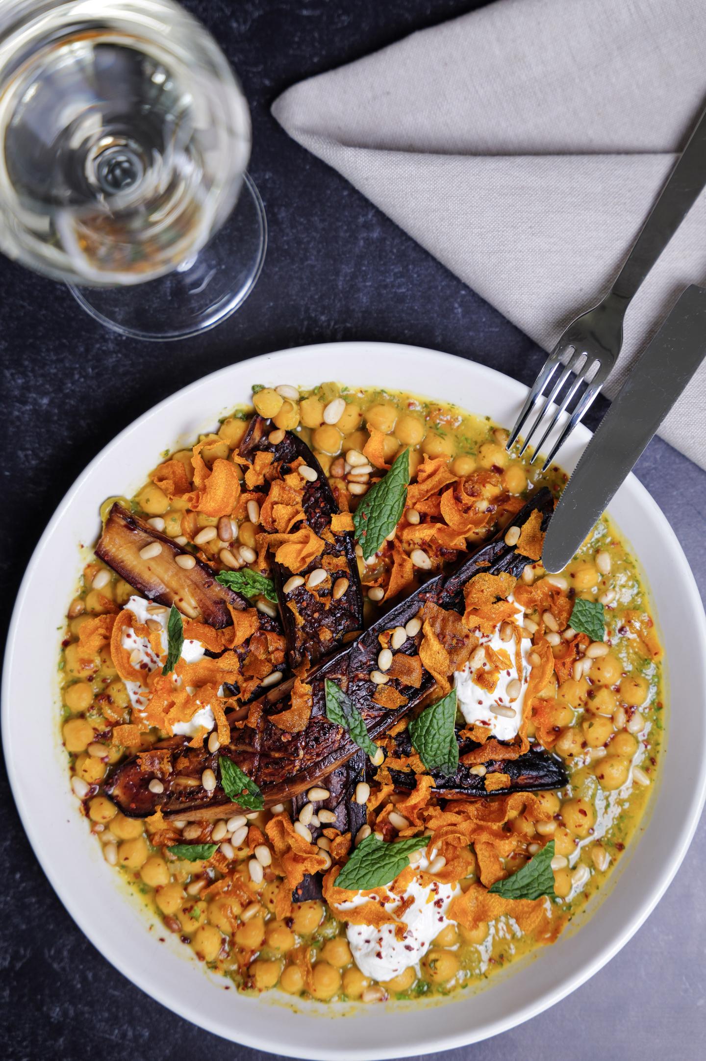 Chickpea salad with roasted carrots and eggplant, garnished with herbs.