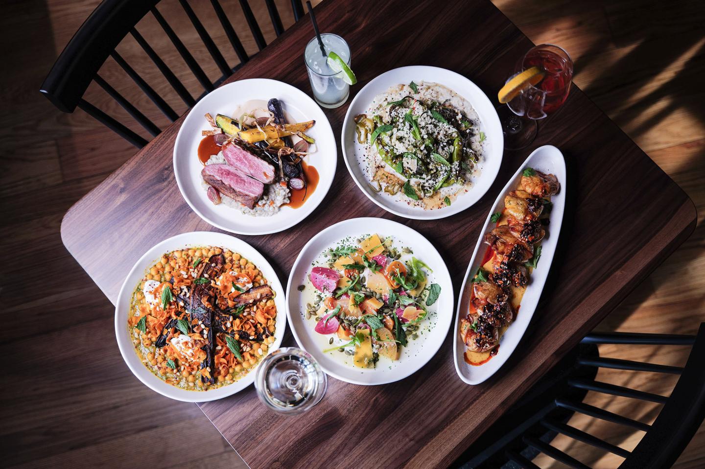 Five plated dishes on a wooden table, ready for serving.