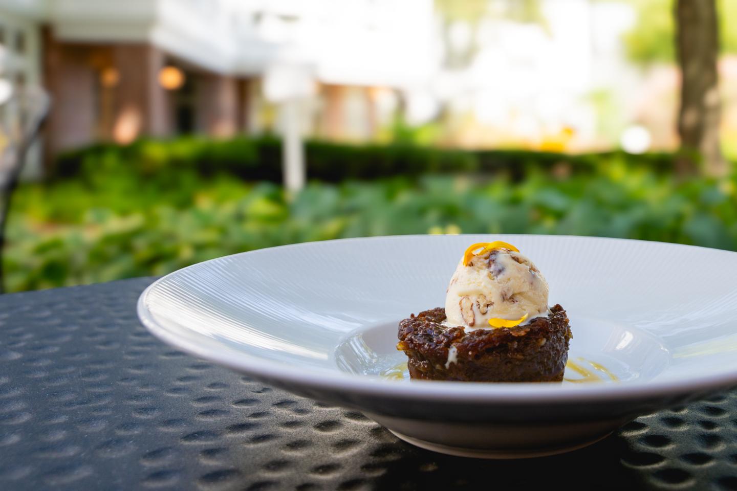 Maple Cake with ice cream on a white plate, outdoor garden setting.