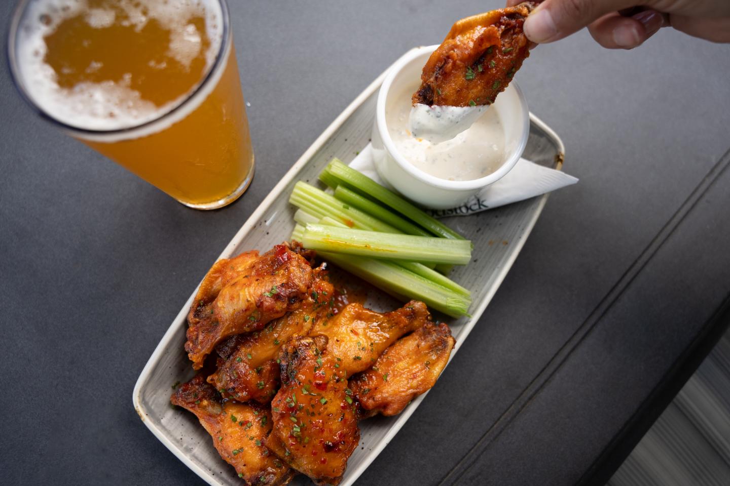 Chicken wings with celery and dip, beer nearby.