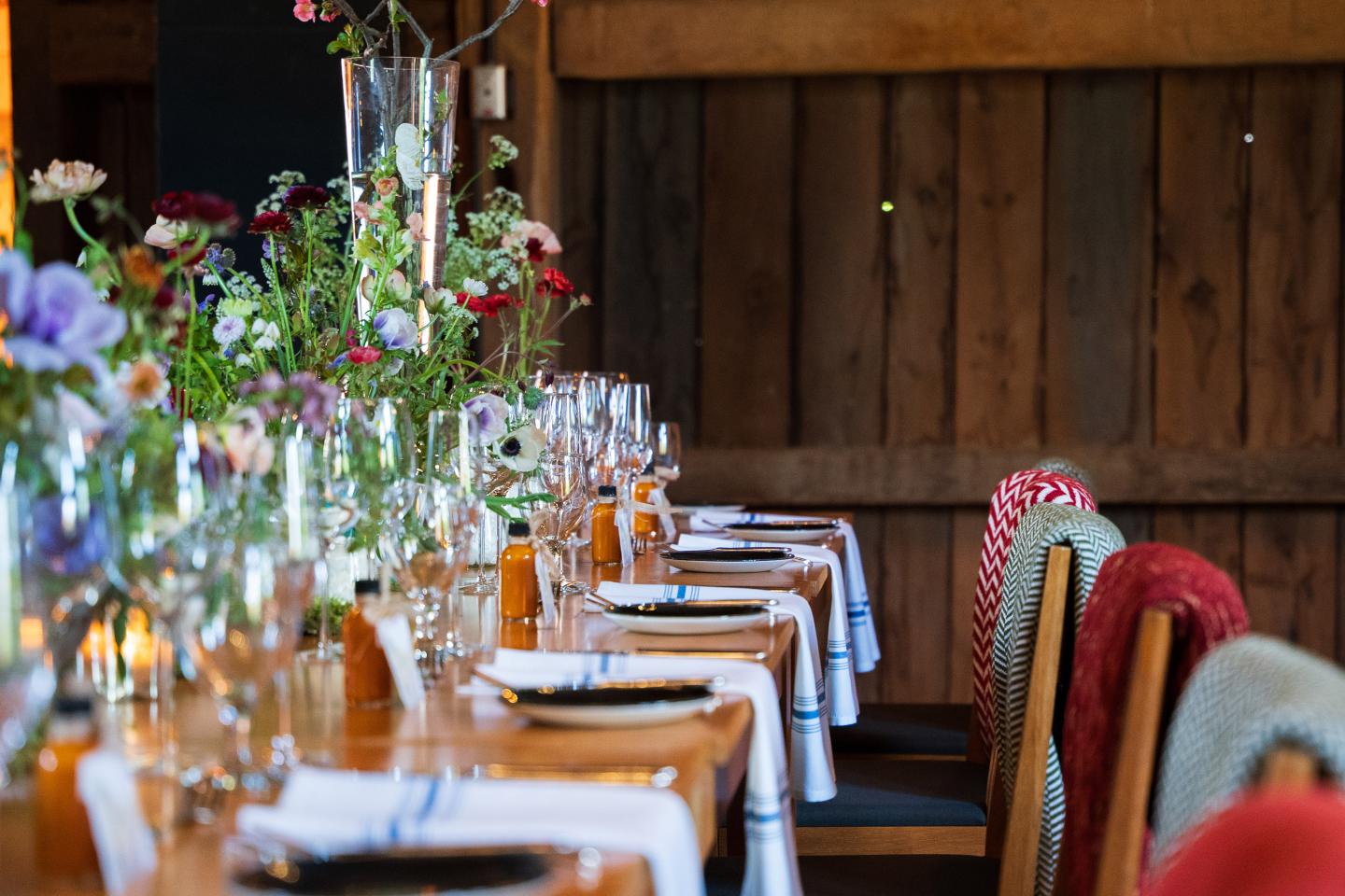 Rustic dining table set with flowers and glassware.