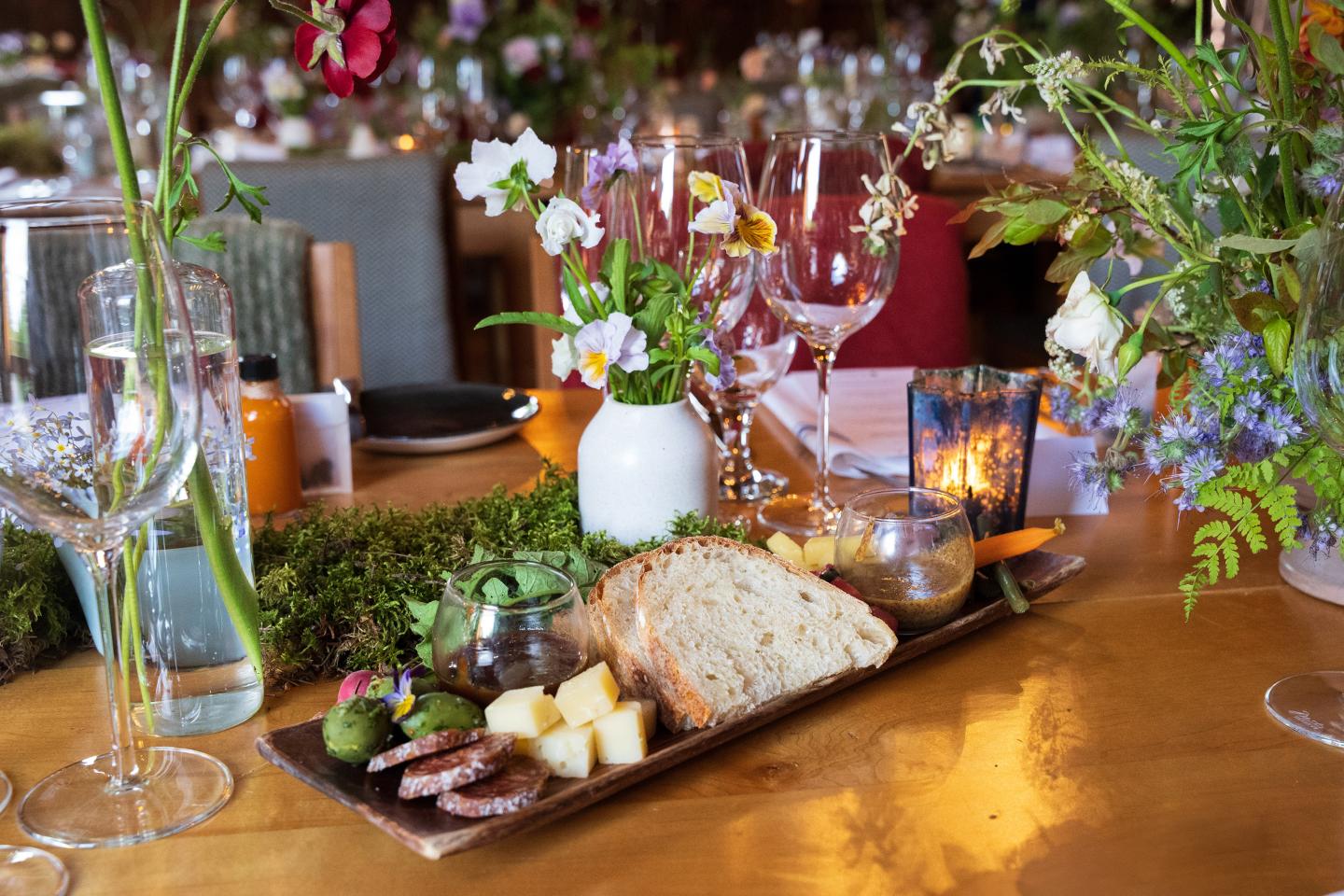 Cheese and bread platter on decorated table with flowers.