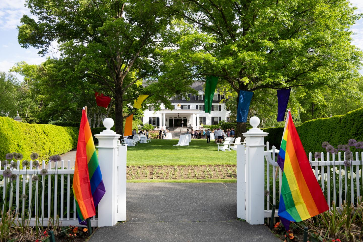 White house and garden with rainbow flags by the entrance gate.