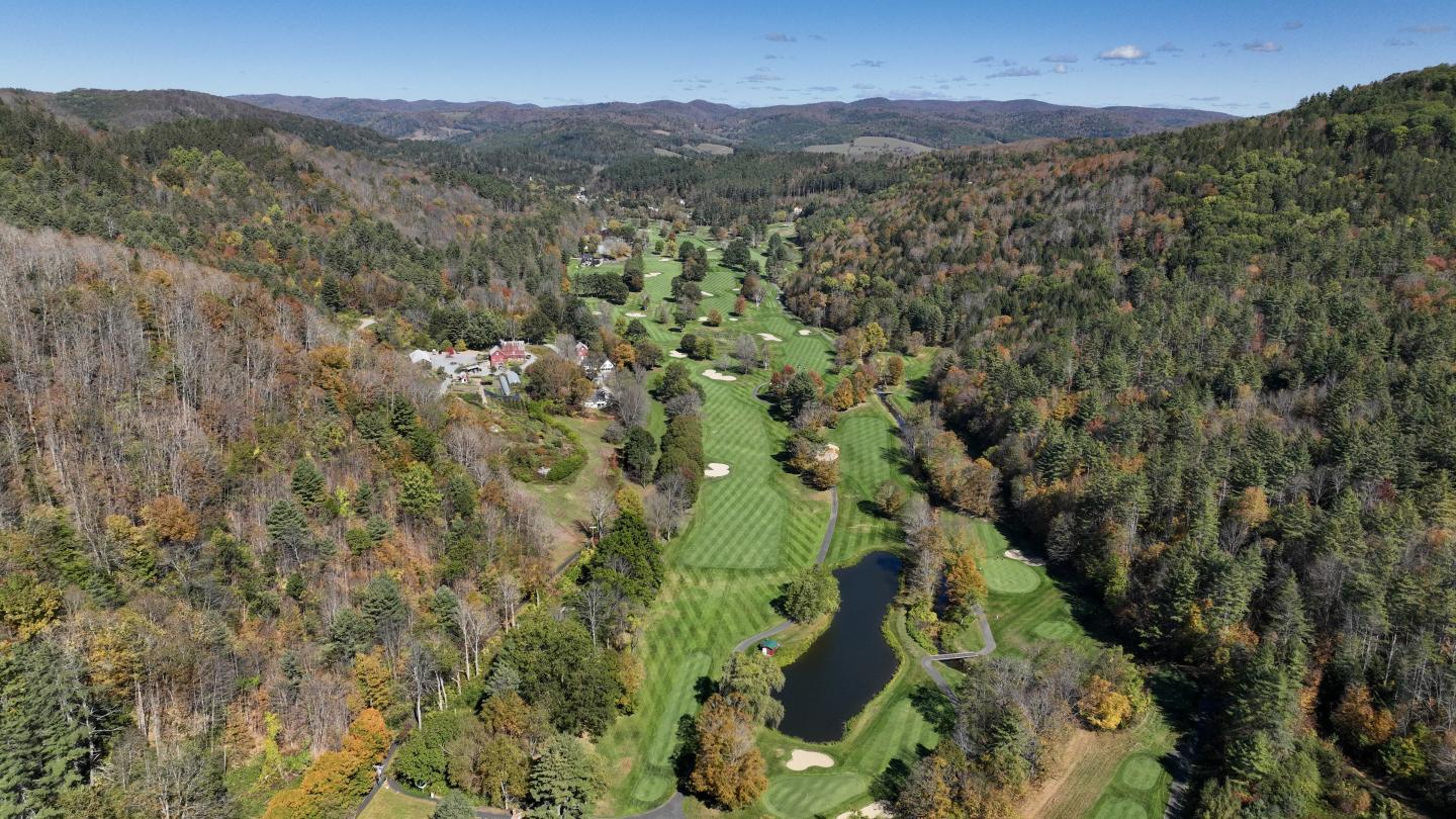 Aerial view of a golf course surrounded by forested hills.