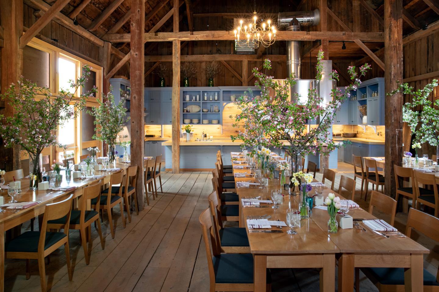 Rustic dining room with wooden tables, floral centerpieces, and a chandelier.
