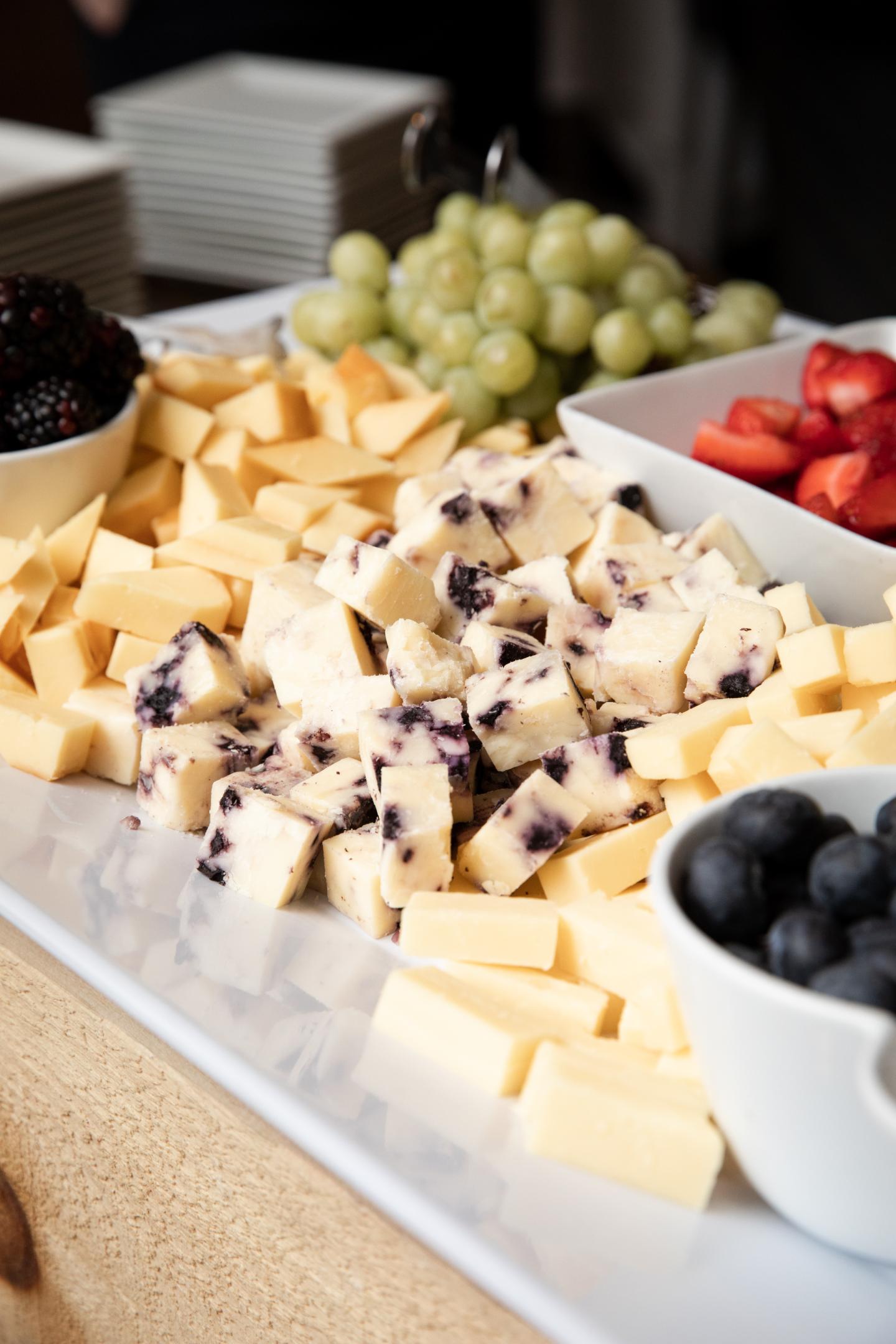 Cheese platter with grapes, berries, and sliced fruit.