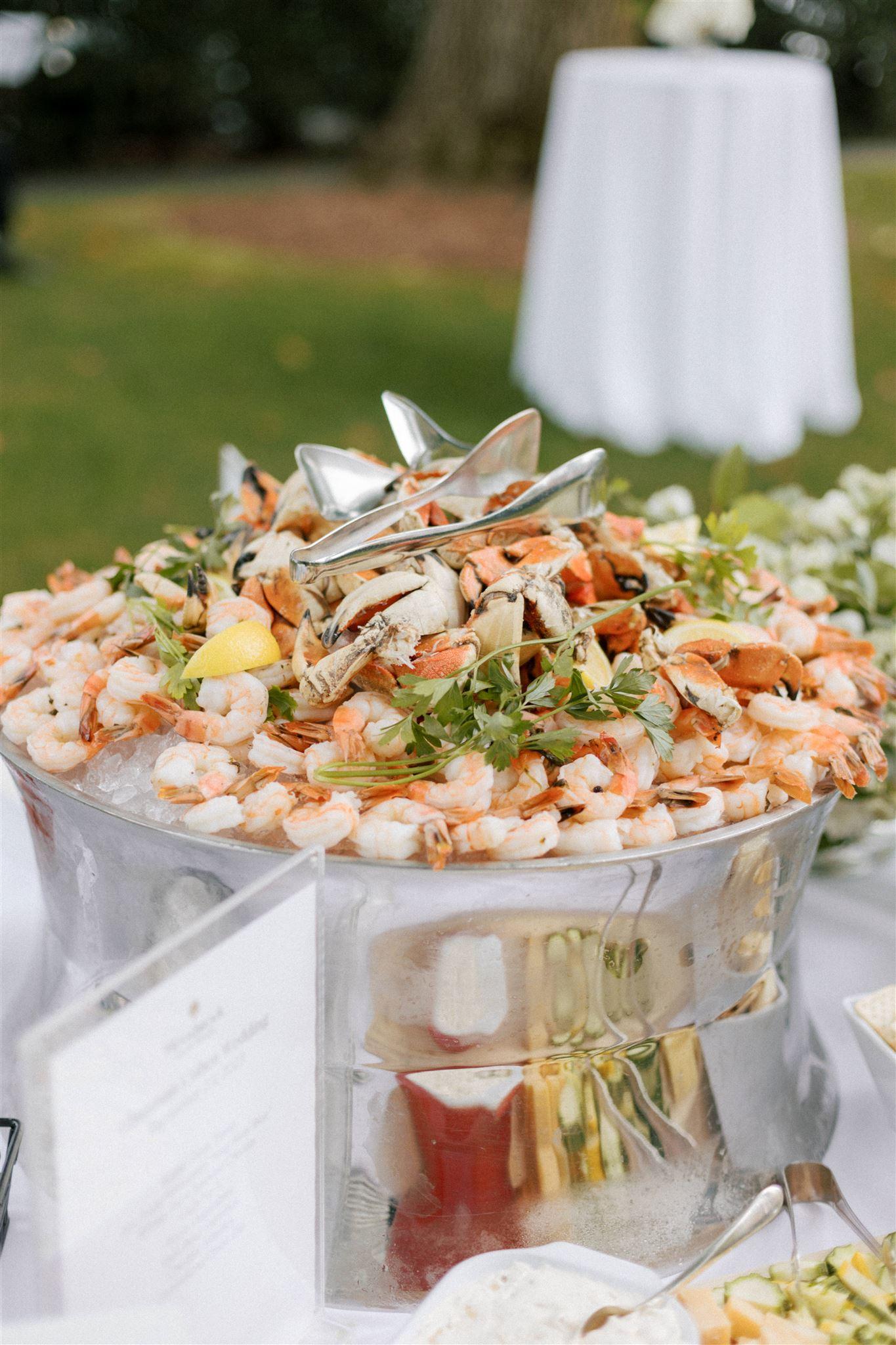 Seafood platter with shrimp, crab, and garnishes on an outdoor table.
