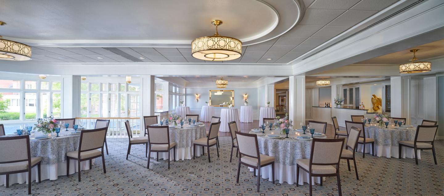 Elegant banquet hall with round tables and white chairs.