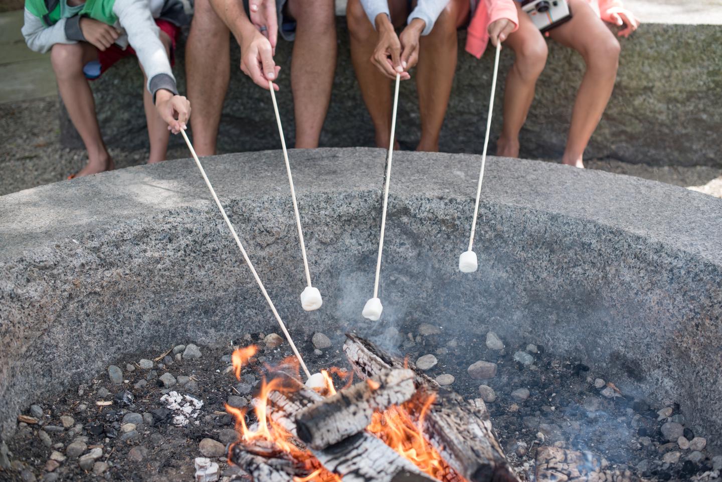 Roasting marshmallows over a campfire in a stone fire pit.