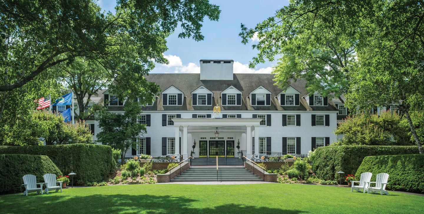 Woodstock Inn & Resort surrounded by green trees and lawn.
