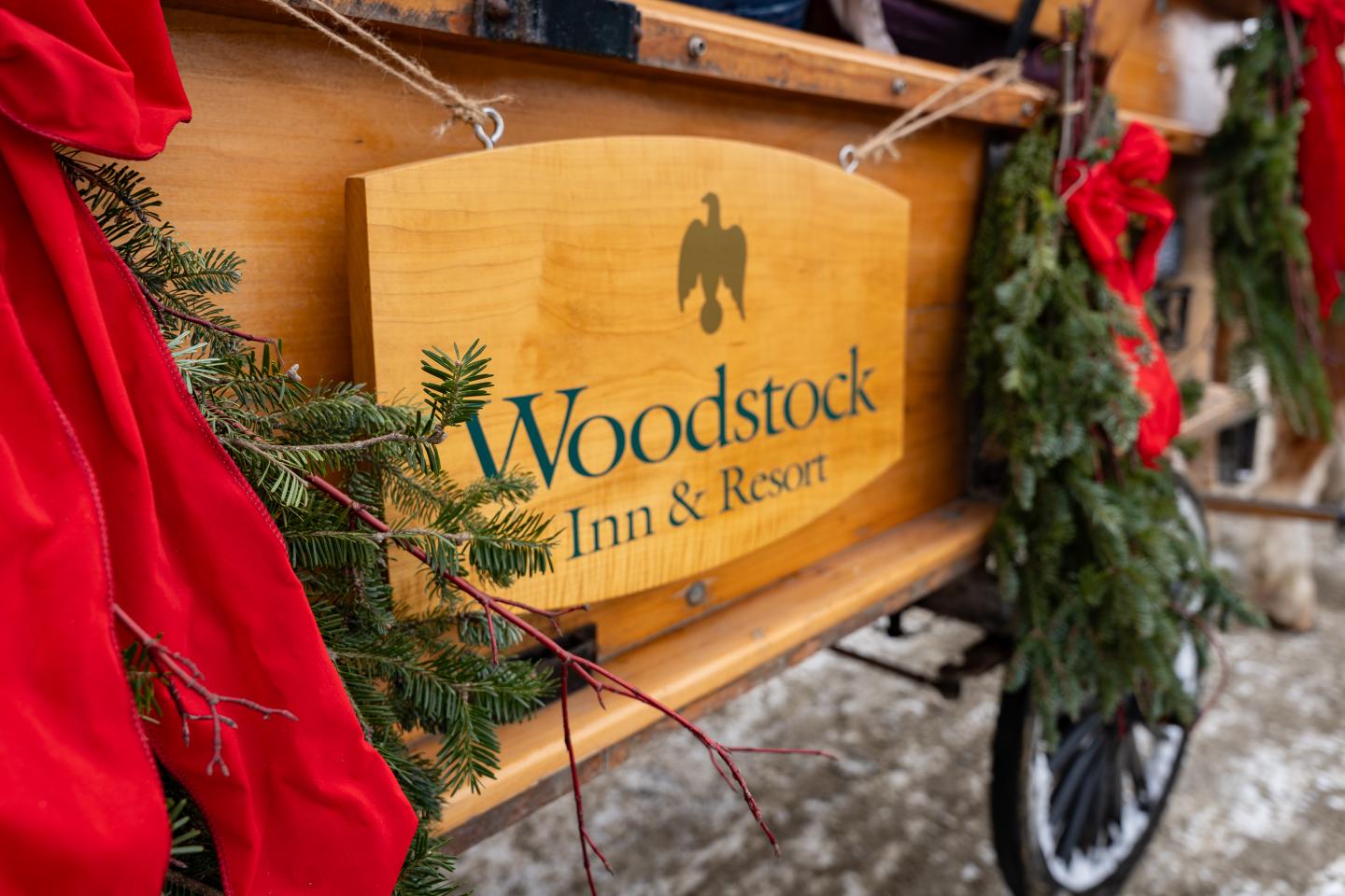 Woodstock Inn wooden sign with festive greenery and red ribbons.